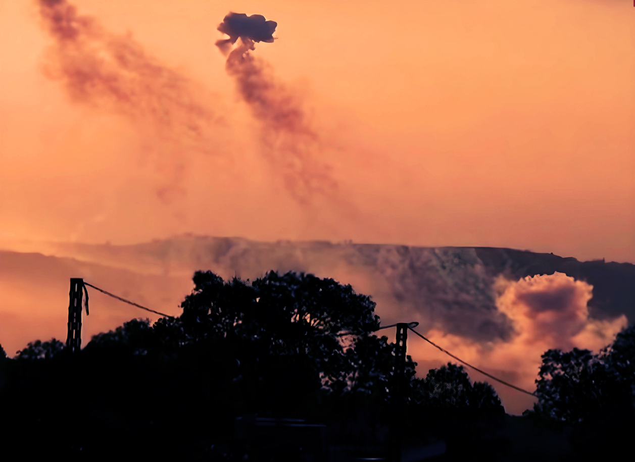 Smoke rising over trees and a power line